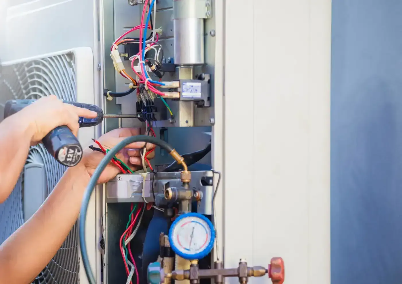 Technician checking refrigerant pressure on an air conditioner.