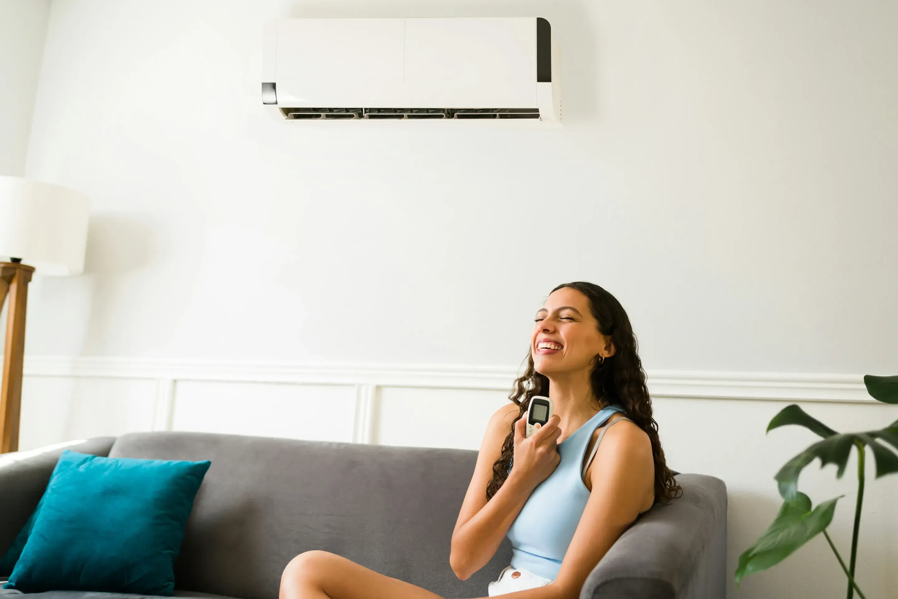 Woman relaxing at home in a comfortably cooled living room.