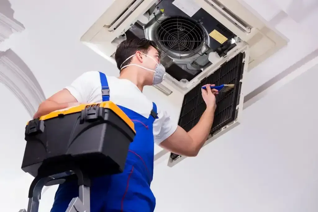 Technician servicing an outdoor air conditioning unit during a maintenance visit.