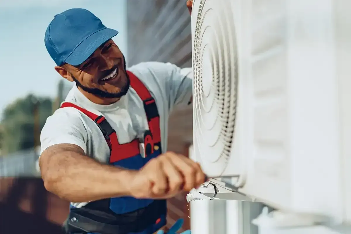 HVAC technician working on air conditioning equipment with insulated piping.