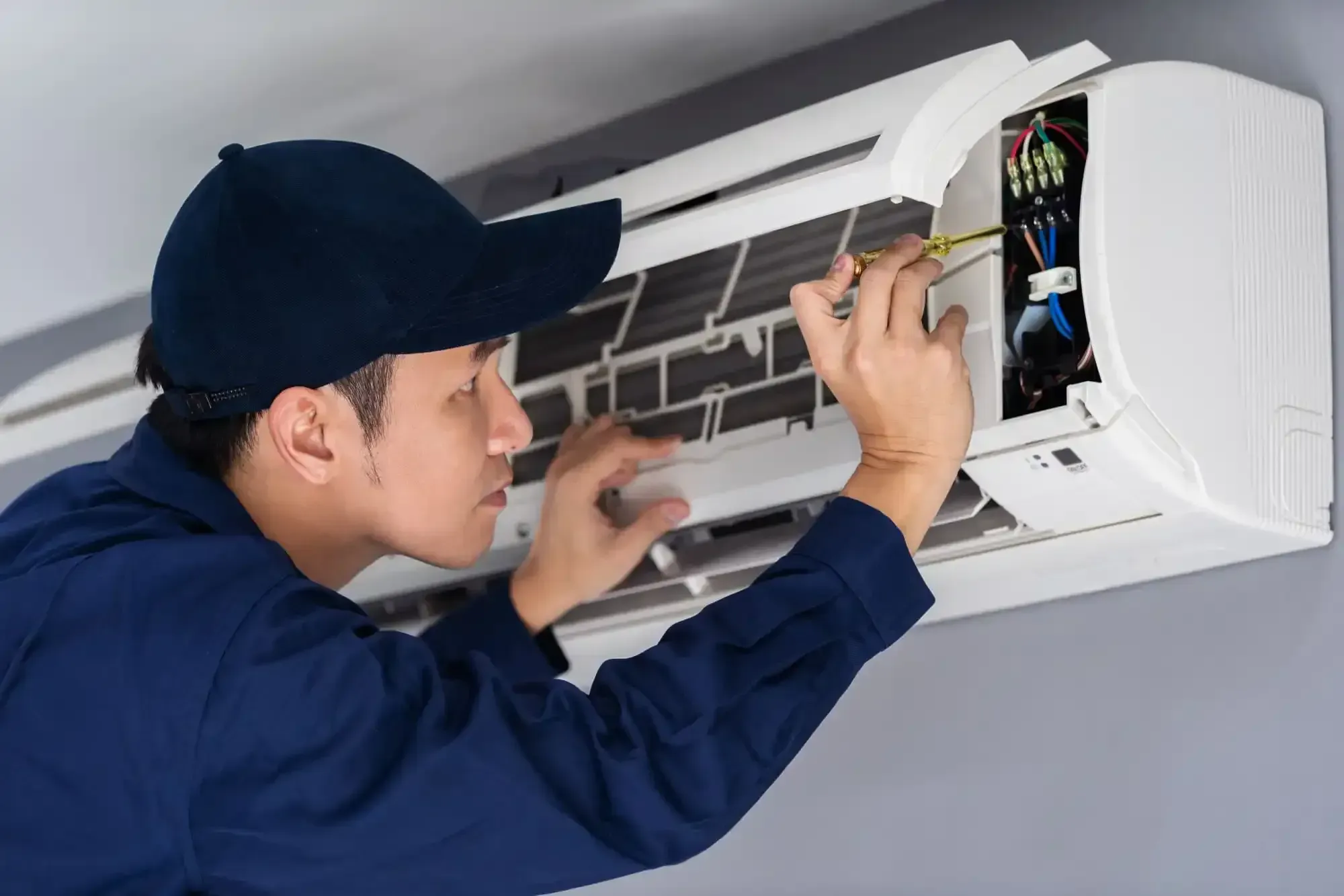 Technician servicing an indoor mini-split air conditioner during a maintenance visit.